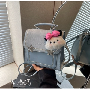 Detail of light blue faux leather backpack with star studs and plush animal charm