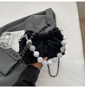 Detail of black pleated cloud bag with marble bead handle and silver chain strap