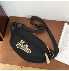 Détail du sac ceinture en nylon noir avec écusson Fashion sur une surface en bois