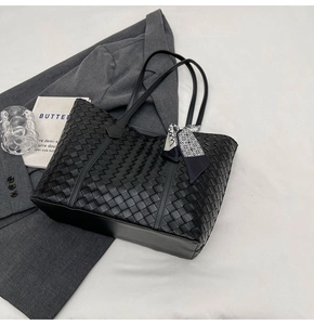 Close-up of black woven tote bag with silk scarf detail and premium leather texture
