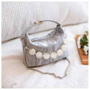 Detail van de kaki crossbody tas met geplooide textuur en stijlvol handvat van grote kralen