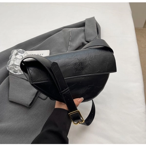 Close-up of black pleated dumpling bag with AKN logo and gold buckle shoulder strap