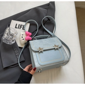 Detail of light blue PU backpack featuring star buckles and pearl trim on grey blazer