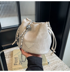 Detail of cream drawstring bucket bag with silver chain strap and velvet texture fabric