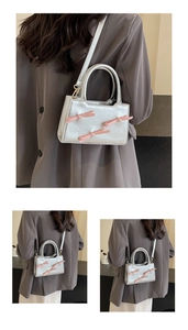 Detail of silver tote bag featuring pink bows with pearl centers and slim shoulder strap