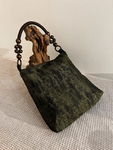 Detailed texture of moss green embroidered tote with rustic wooden bead handle