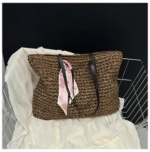 Close-up of deep brown straw woven tote with leather handle and decorative silk scarf