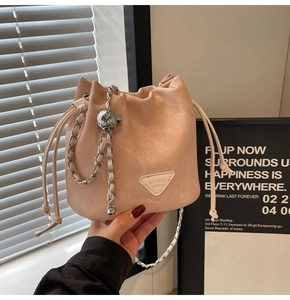 Detail of light pink drawstring bucket bag with silver chain and metal ball ornament