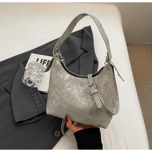 Detail of silver metallic textured underarm bag with unique cracked leather pattern and strap