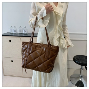 Close-up of brown quilted leather tote bag with elegant rectangular metal logo plate