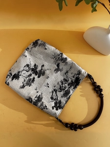 Detail of moss green tote featuring ink landscape pattern and wooden beaded handle