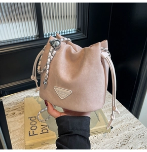 Detail of pink drawstring bucket bag with silver chain strap and triangle logo plate