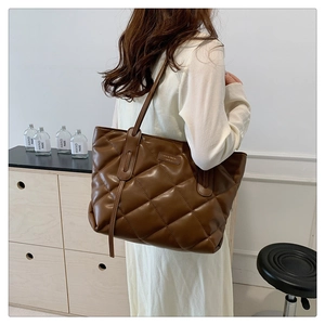 Detail of a brown quilted tote bag with diamond stitching and elegant long shoulder straps
