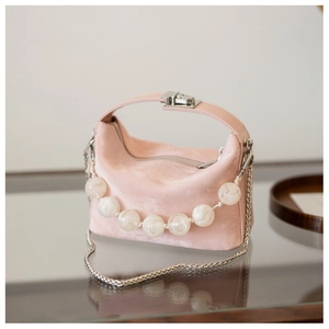Detail van roze suède handtas met grote marmeren kralenketting en zilveren metalen sluiting