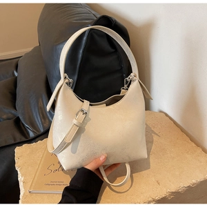 Detailed macro view of the cream leather bag showing unique crackle texture and metal hardware