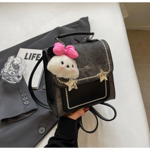 Detail of vintage style leather and denim bag with star metal buckles and plush charm