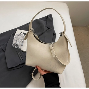 Detail of minimalist cream half-moon shoulder bag with wrinkled texture and silver buckle