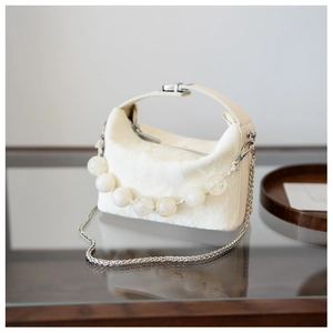 Detail van beige crossbodytas met geplooide textuur en handvat van grote harskralen