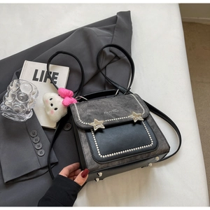 Detail of grey crossbody bag with star studs, faux pearls and pink bow plush charm