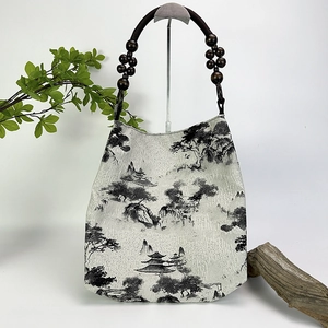 Close-up of moss green tote bag with traditional ink landscape painting and wooden beads