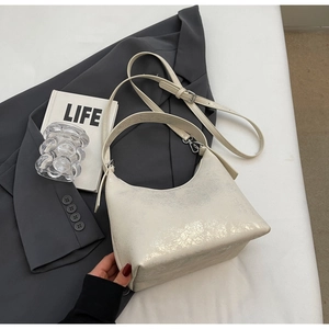 Detail of white textured hobo bag with adjustable strap on a gray blazer setting