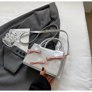 Detail of silver mini tote with pink bows and pearl accents on textured metallic surface