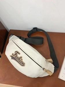 Sac banane de sport blanc avec écusson 'Fashion' brodé sur une table en bois
