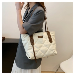 Detail of quilted beige tote bag with brown straps and fashion embossed leather tag