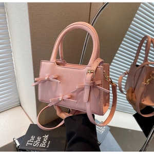 Detail of pink croc-embossed tote bag with 3D bows, pearl accents and gold hardware