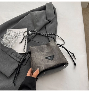 Close-up of vintage grey canvas bucket bag with chain strap and leather logo patch