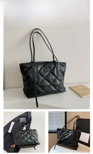 Close-up of black quilted faux leather tote bag with gold metal logo and slim straps