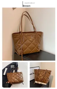 Detail view of large brown tote bag with diamond quilted pattern and shoulder straps