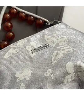 Close-up of silver floral jacquard fabric and amber bead handle on retro handbag