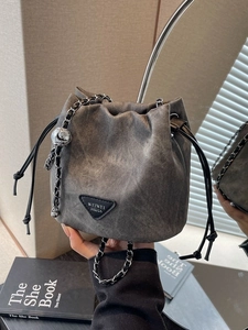 Minimalist drawstring bucket bag in washed grey fabric with metal chain and leather strap