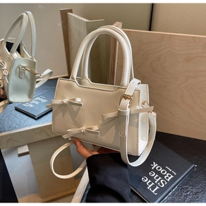 Close-up of off-white tote bag featuring three 3D bows and textured faux leather finish