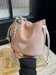 Pale pink drawstring bucket bag with a chain strap and triangle logo plate detail