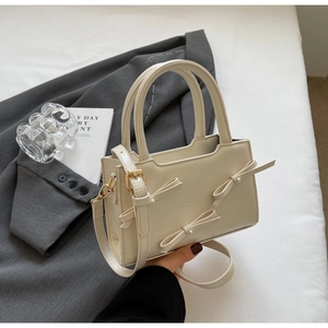 Detailed shot of off-white tote bag featuring 3D bow ornaments and pearl accents