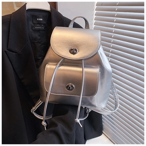 Detail of metallic silver backpack with twist-lock buckles on a dark suit background
