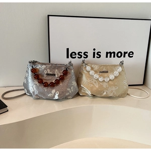 Detailed view of beaded handles on silver and gold butterfly print handbags for women