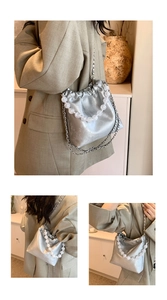 Detail showing silver bucket bag with beaded handle, chain strap, and floral texture