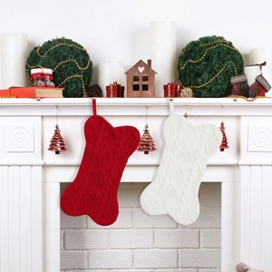 Primer plano de calcetines de Navidad de punto en forma de hueso colgados en chimenea