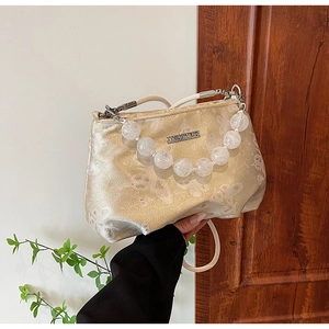 Detail of champagne gold jacquard handbag with butterfly patterns and beaded strap