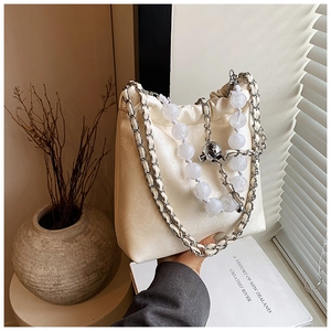 Close-up of cream leather shoulder bag with vintage embossing and bead chain detail