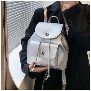 Detail of silver metallic backpack with turn-lock closure and drawstring on black blazer