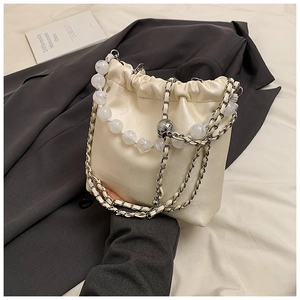Detail of cream white bucket bag with elegant pearl and metal chain on a suit jacket