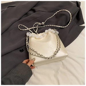 Detail of cream white bucket bag featuring floral jacquard texture and frosted beads