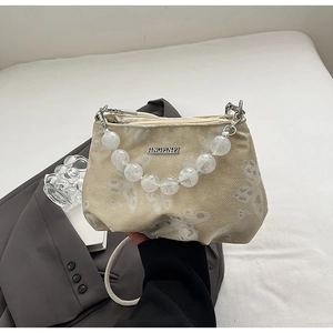 Detailed macro view of cream-colored beaded handbag with white butterfly patterns