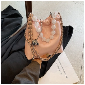 Detailed shot of pink leather bucket bag with white pearl handle and metal chain strap