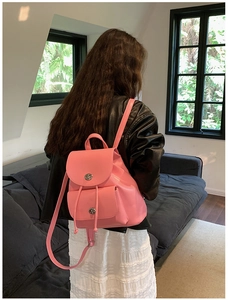 Pink leather mini backpack with flap drawstring and silver buckle shown on a model