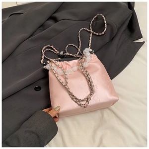 Close-up of pink satin drawstring bucket bag featuring floral jacquard and beaded chain